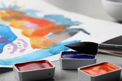 Abstract watercolor painting, colorful paints and brush on grey table, closeup