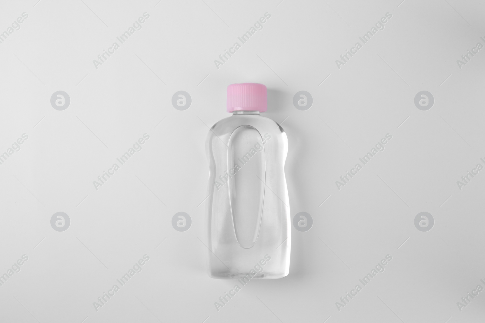 Photo of Transparent bottle with baby oil on white background, top view