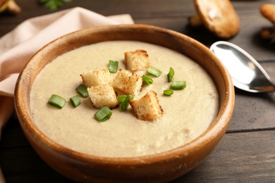 Photo of Bowl of fresh homemade mushroom soup on wooden table