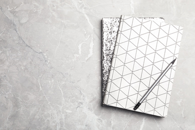 Photo of Stylish notebooks and pencil on marble table, top view. Space for text