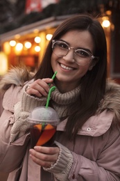 Woman with cup of mulled wine at winter fair