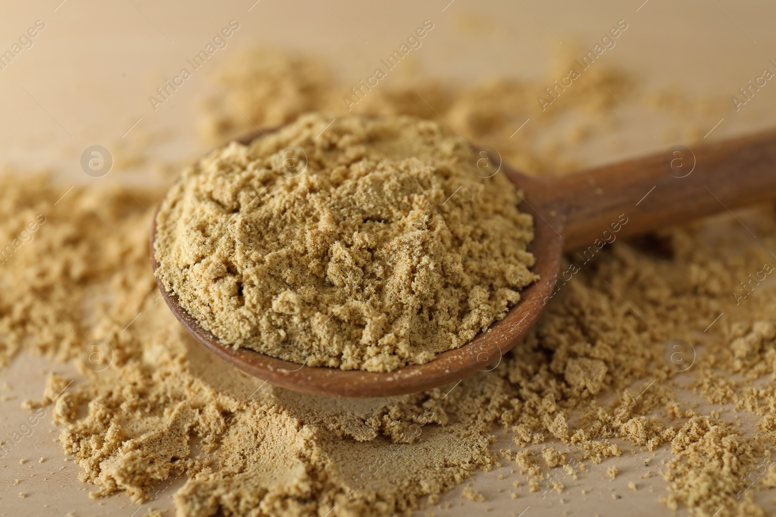 Photo of Spoon with aromatic mustard powder on wooden table, closeup