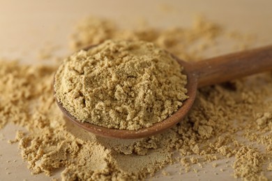 Photo of Spoon with aromatic mustard powder on wooden table, closeup