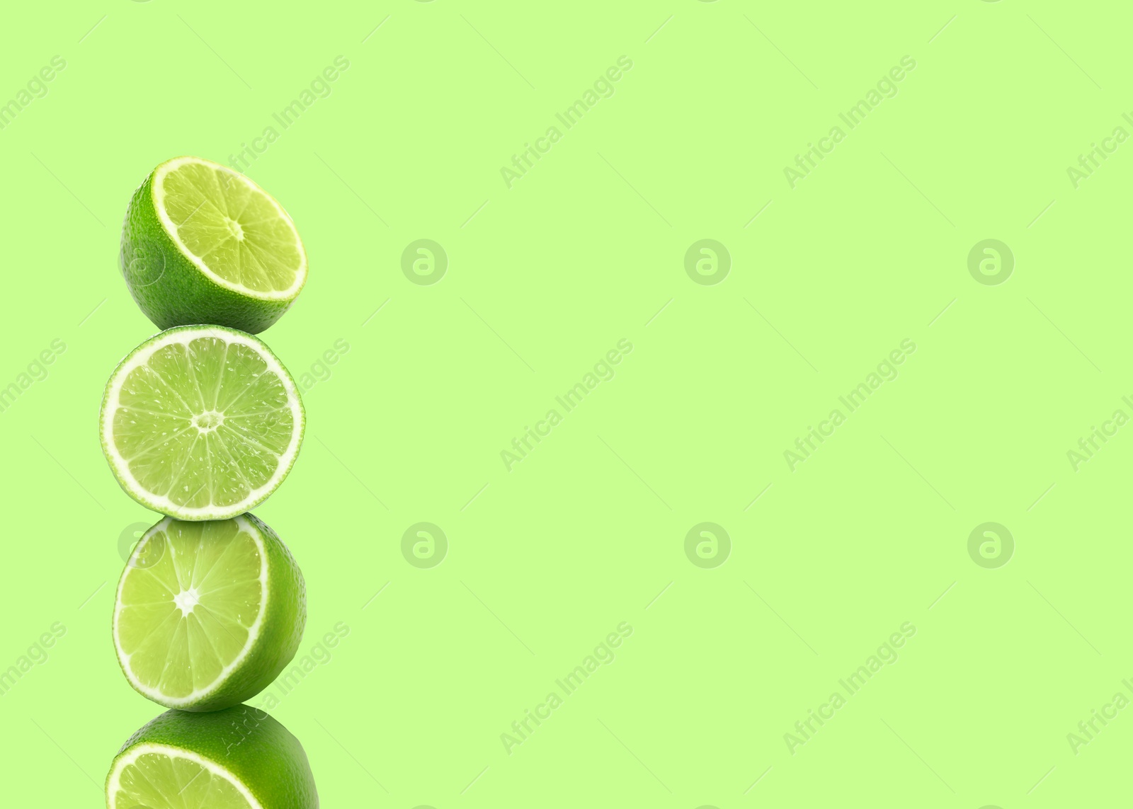 Image of Stacked cut limes on light green background, space for text