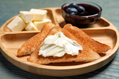 Photo of Tasty toasts with butter and blueberry jam on light blue wooden table, closeup