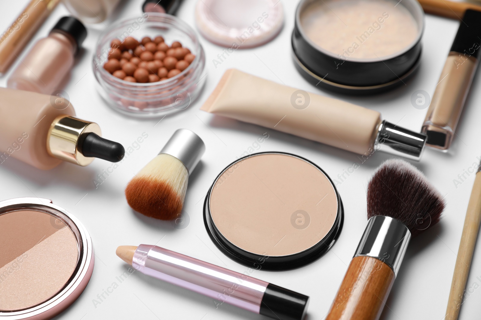 Photo of Face powders and other makeup products on white background, closeup