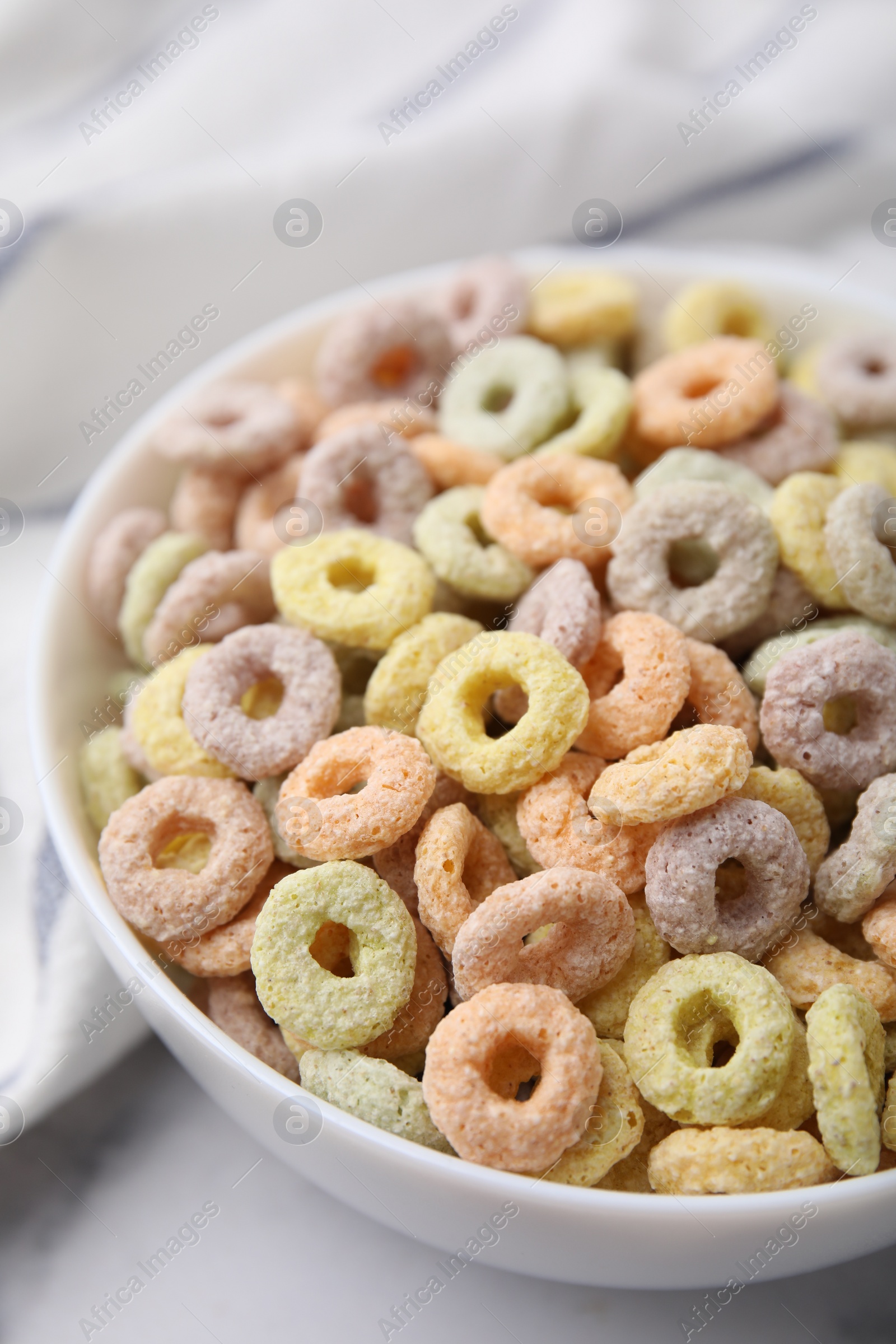 Photo of Tasty cereal rings in bowl on white table, closeup