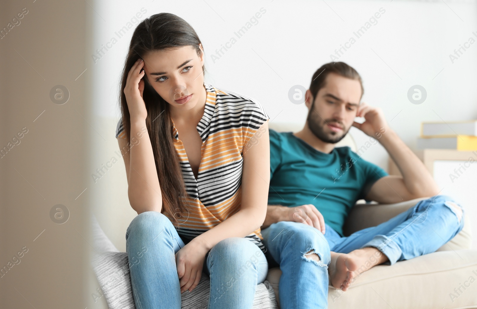 Photo of Young couple ignoring each other after having argument in living room