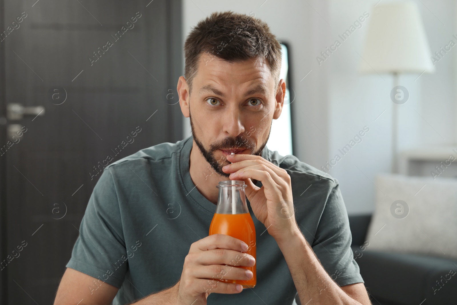 Photo of Man drinking delicious juice from bottle at home