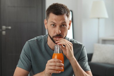 Photo of Man drinking delicious juice from bottle at home