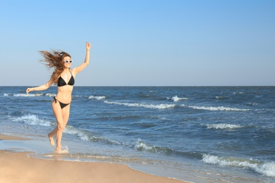 Beautiful woman in bikini on sea coast. Space for text