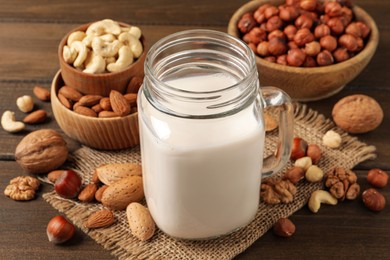 Vegan milk and different nuts on wooden table