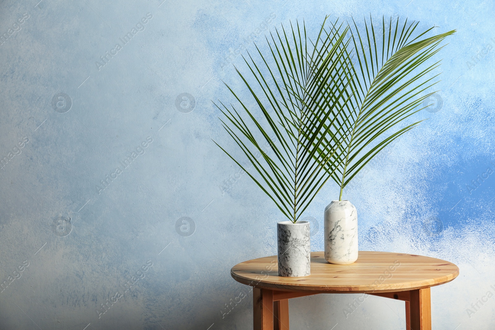 Photo of Vases with tropical Date palm leaves on table. Space for text