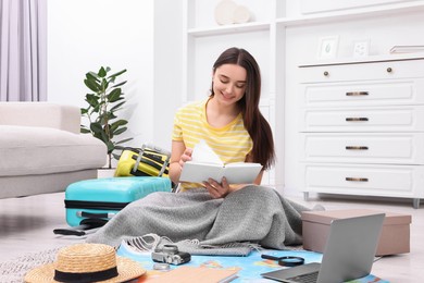 Travel blogger with book and other items planning trip at home