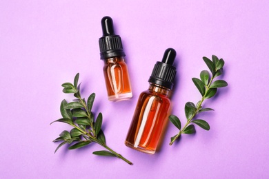 Flat lay composition with cosmetic bottles of essential oils on color background
