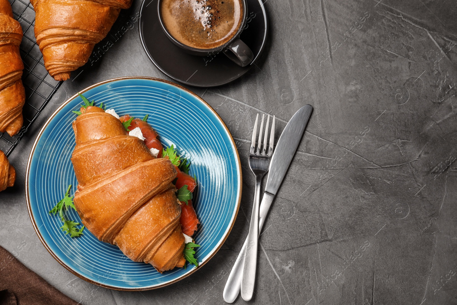 Photo of Tasty croissant sandwich with red fish on grey table, flat lay. Space for text