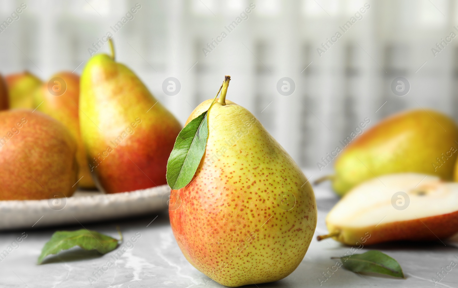 Photo of Ripe juicy pears on grey stone table against light background