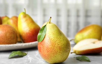 Ripe juicy pears on grey stone table against light background