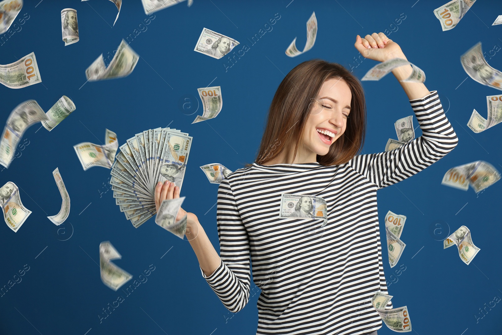 Image of Happy young woman with dollars under money rain on blue background
