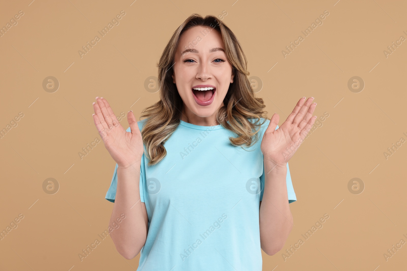 Photo of Portrait of happy surprised woman on beige background