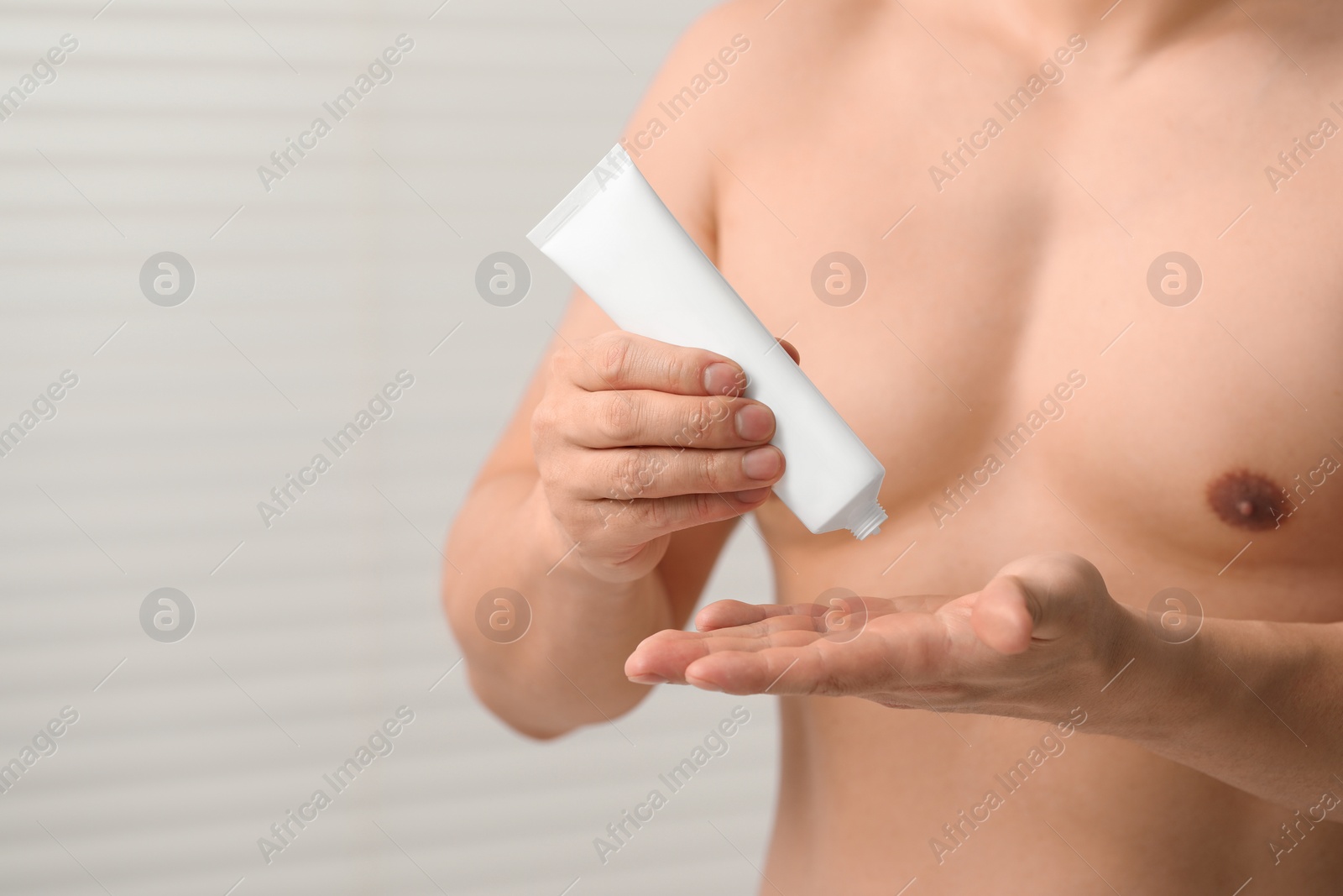 Photo of Man applying body cream onto his hand indoors, closeup. Space for text