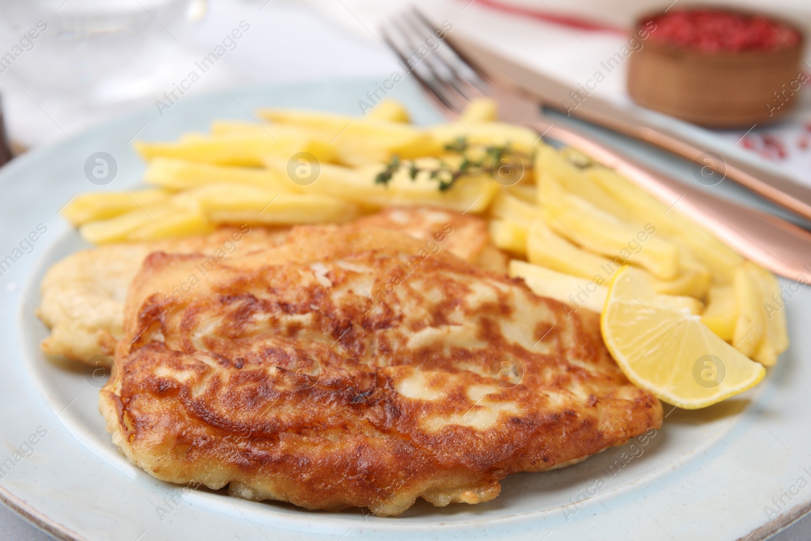 Photo of Tasty soda water battered fish, potato chips and lemon slice on plate, closeup