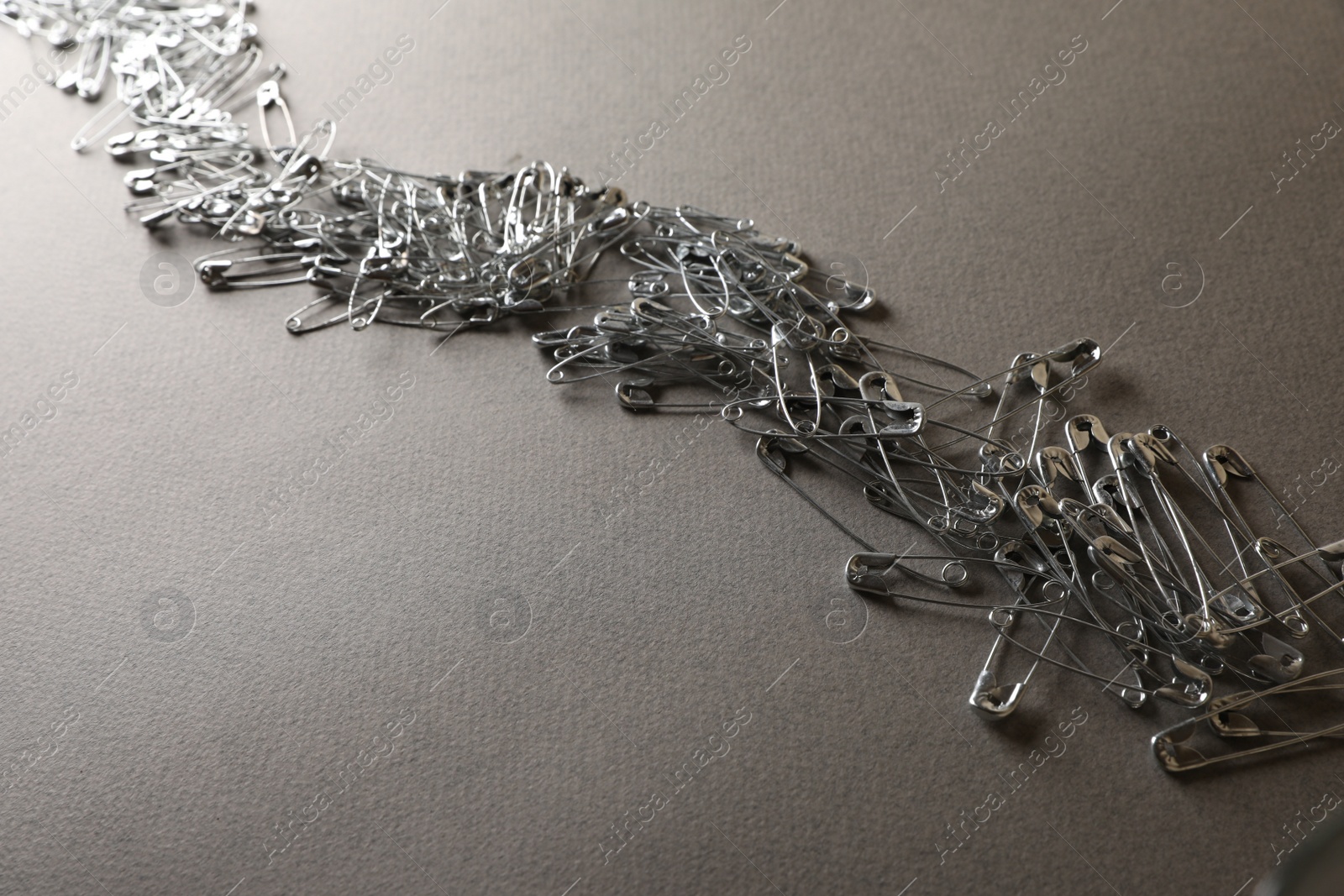 Photo of Many safety pins on light grey textured background