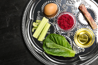 Photo of Passover Seder plate (keara) on black table, top view. Pesah celebration