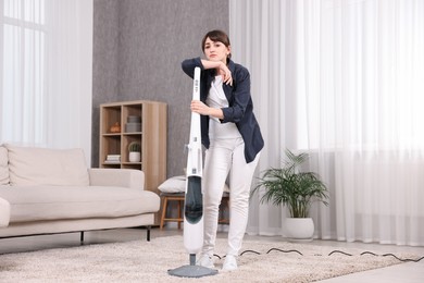 Tired young housewife cleaning carpet at home