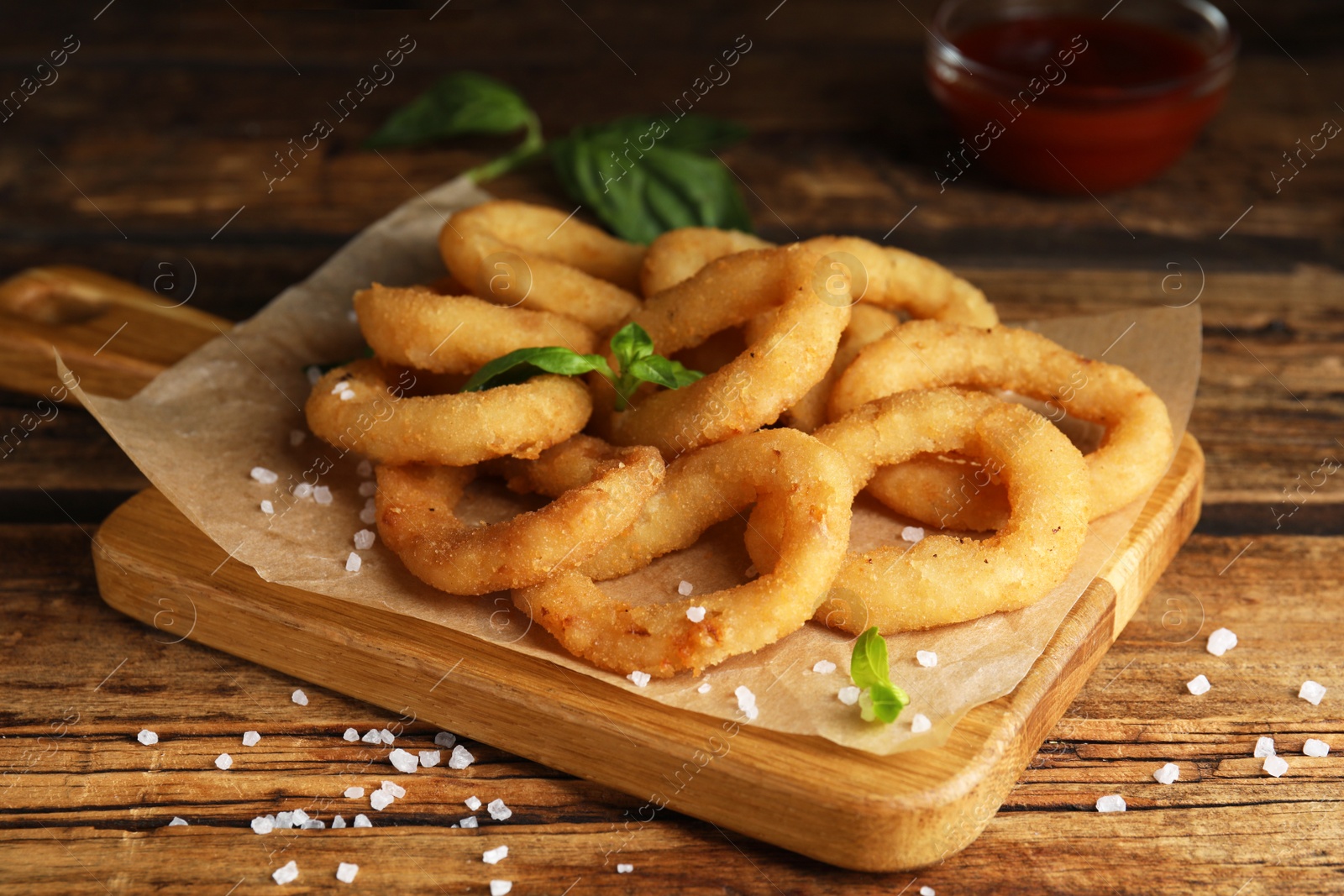 Photo of Delicious onion rings on wooden table, closeup