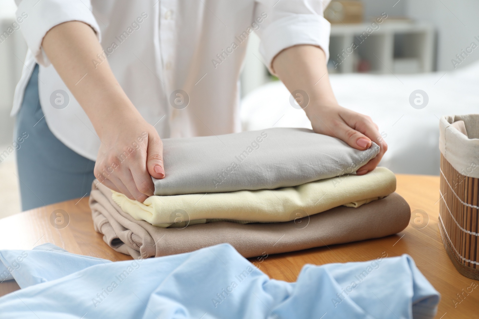 Photo of Woman folding clothes at wooden table indoors, closeup