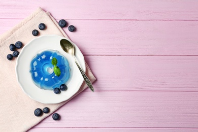 Plate of delicious blue jelly with berries on pink wooden background, flat lay. Space for text