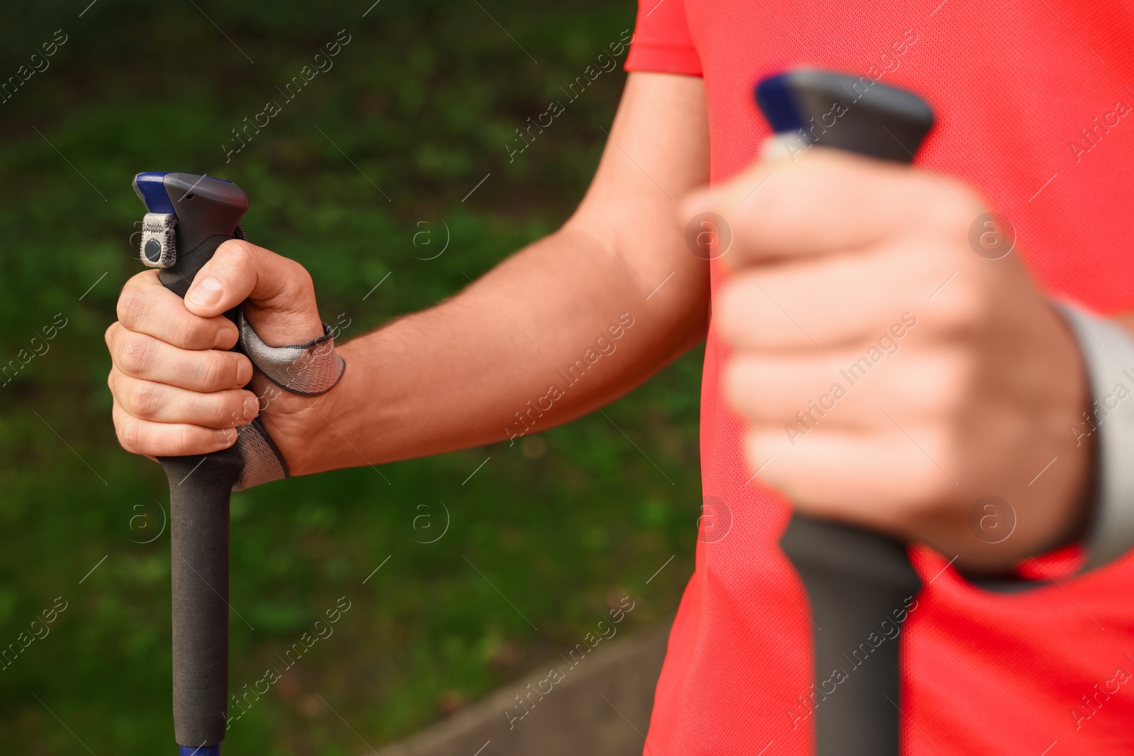 Photo of Man practicing Nordic walking with poles outdoors, closeup