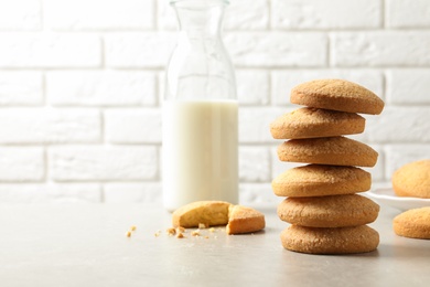 Photo of Stack of Danish butter cookies and milk on table against brick wall. Space for text