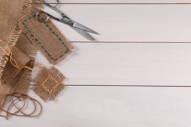 Flat lay composition with pieces of burlap fabric on white wooden table, space for text