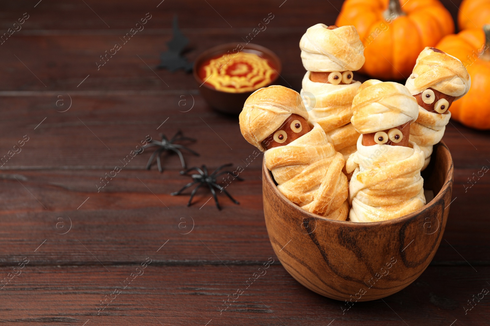 Photo of Spooky sausage mummies for Halloween party served on wooden table, space for text