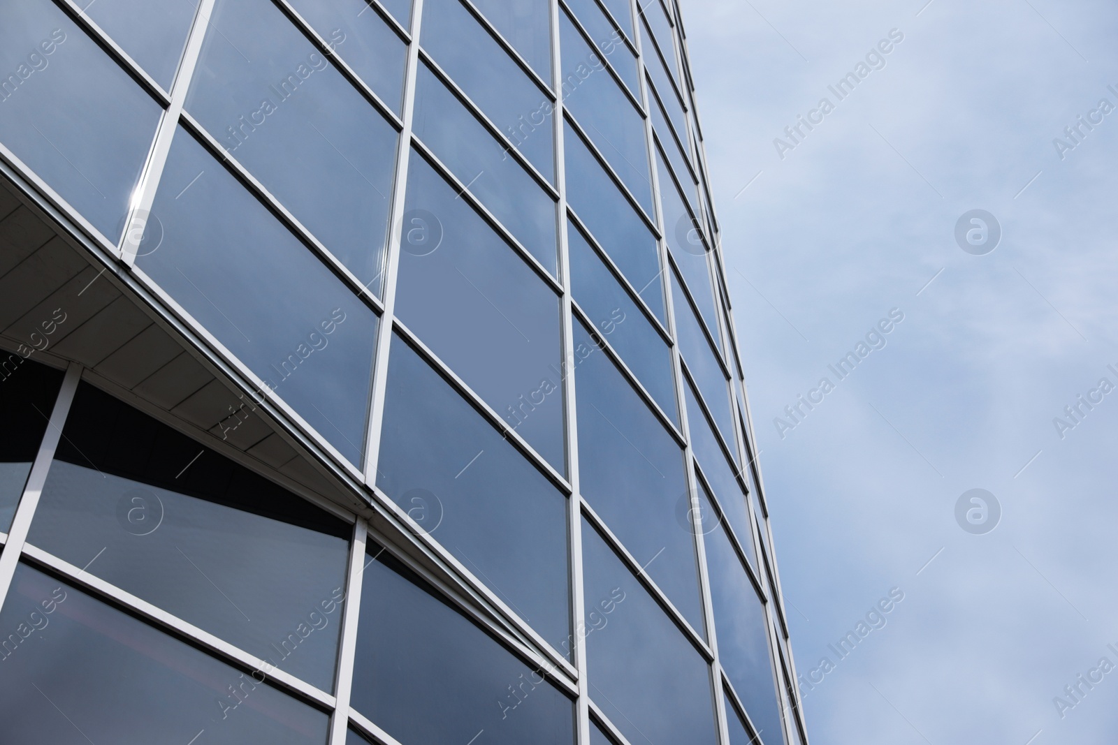 Photo of Modern building with tinted windows against sky, low angle view. Urban architecture