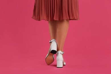 Woman wearing stylish shoes on pink background, closeup