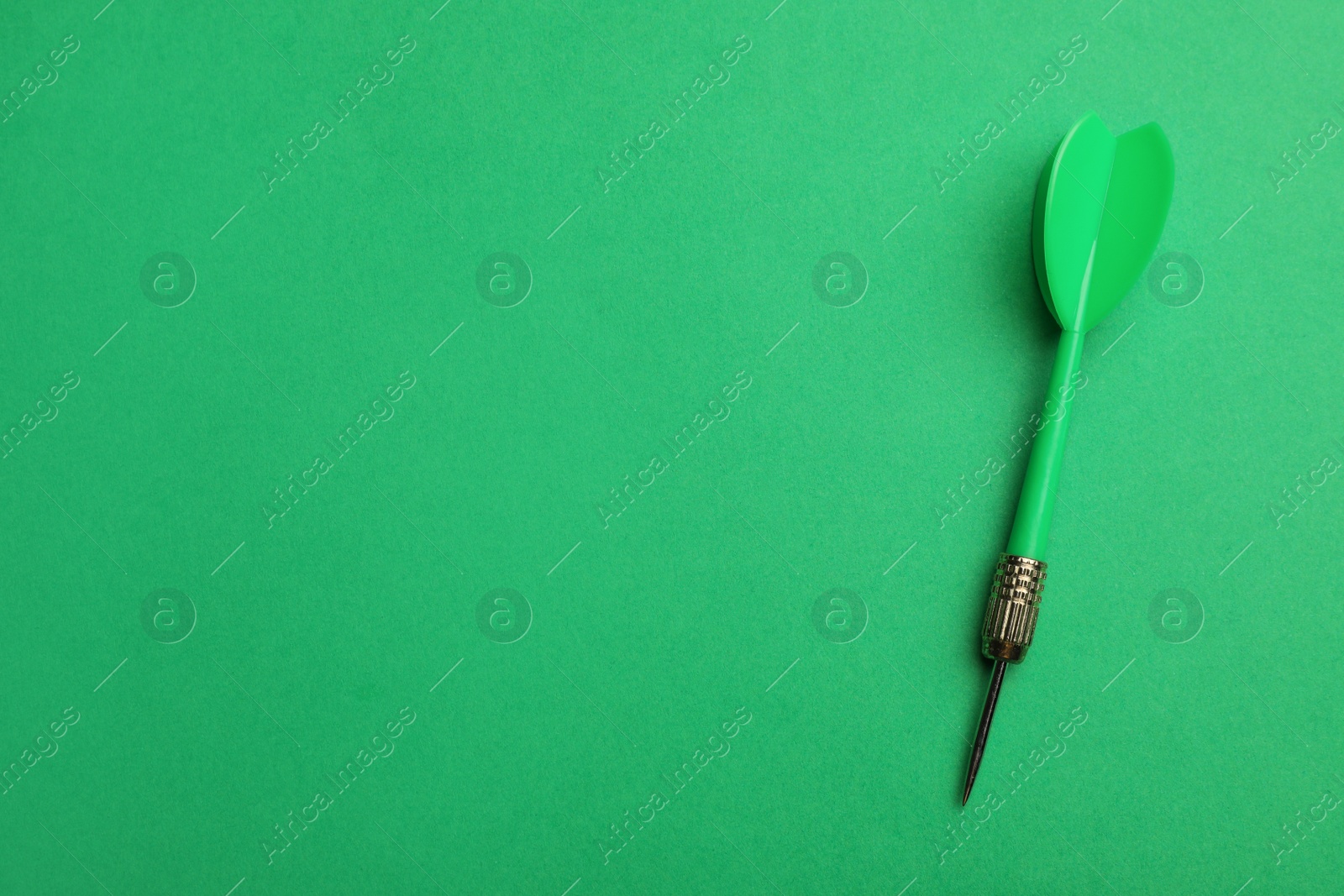 Photo of Plastic dart arrow on green background, top view with space for text