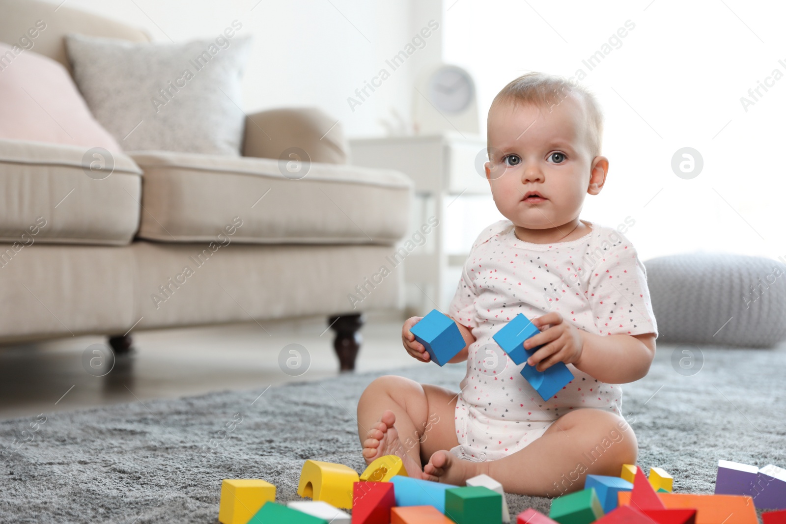 Photo of Cute baby girl playing with building blocks in room. Space for text