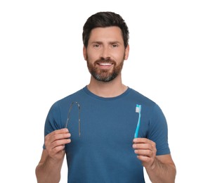Happy man with tongue cleaner and plastic toothbrush on white background