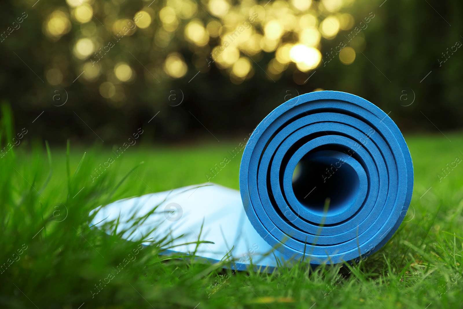 Photo of Bright karemat or fitness mat in fresh green grass outdoors, closeup