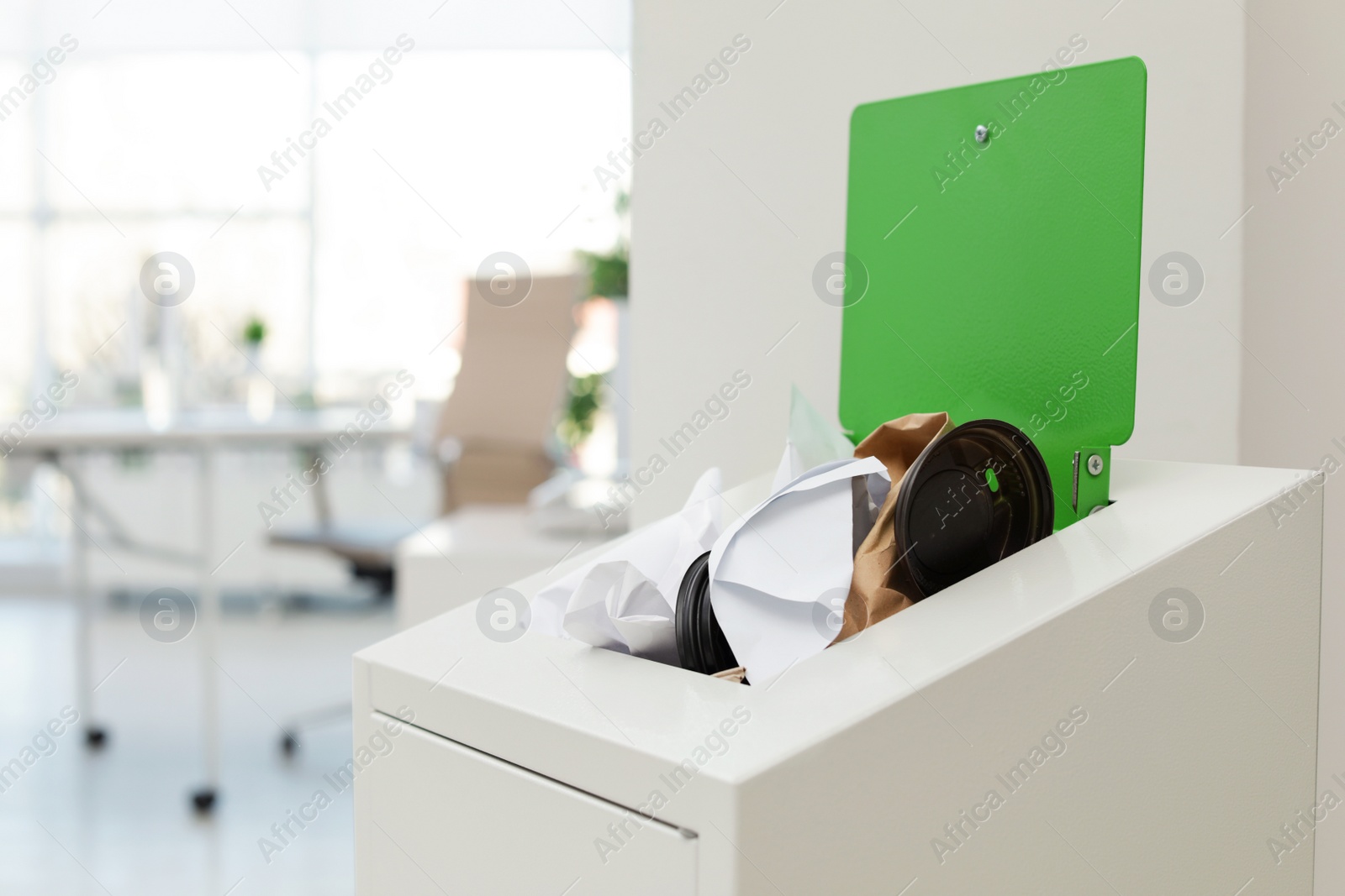 Photo of Open full trash bin in modern office, space for text. Waste recycling