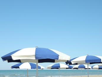 Many blue and white beach umbrellas near sea