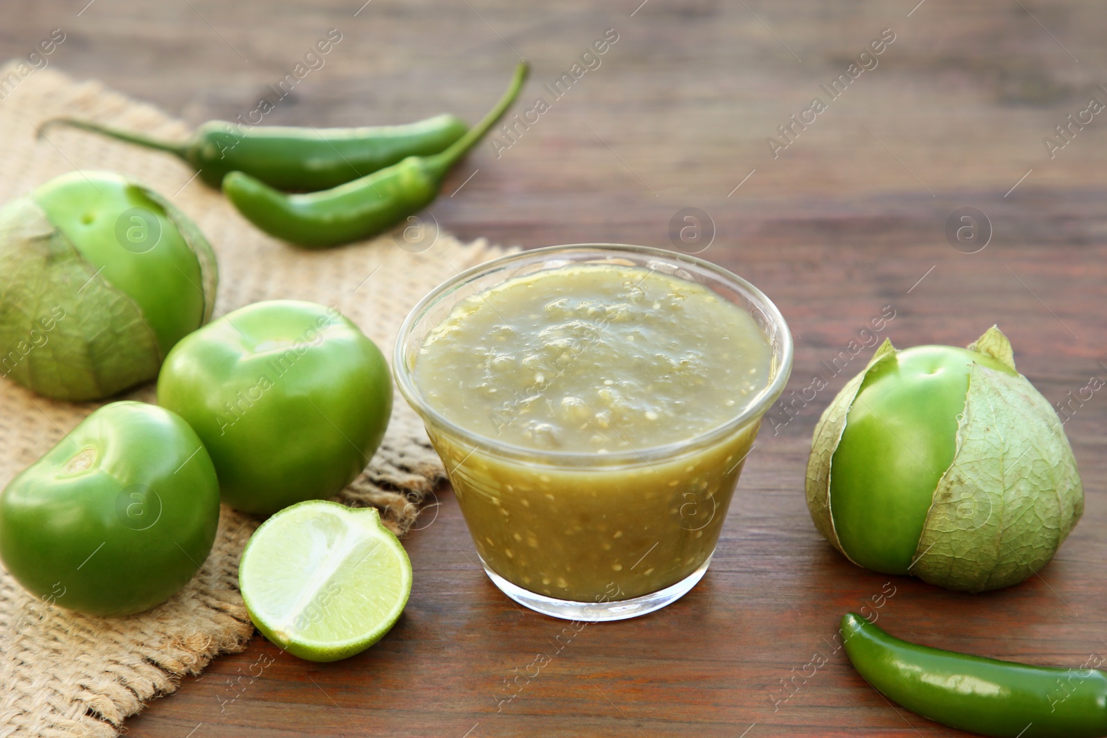 Photo of Tasty salsa sauce and ingredients on wooden table, closeup