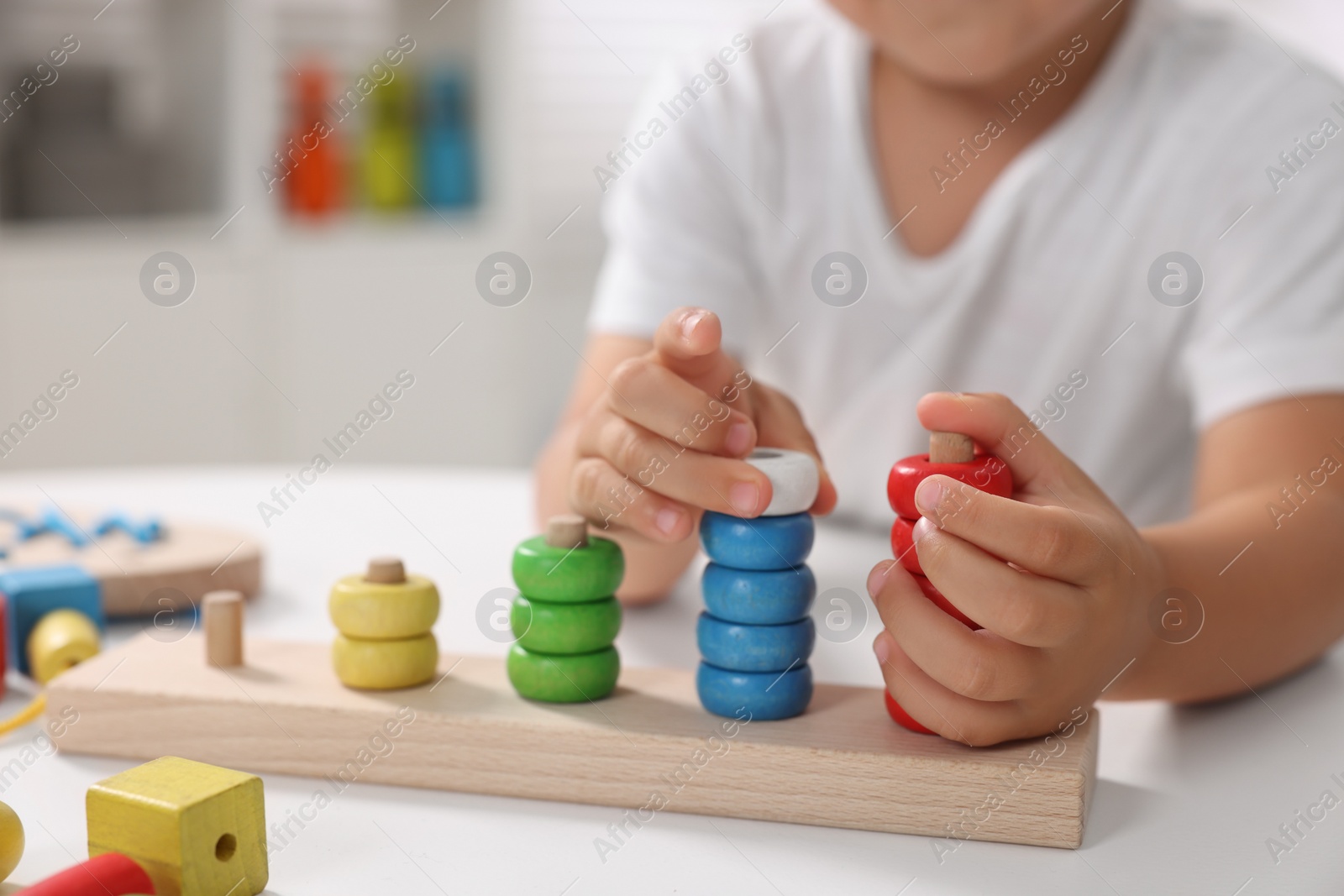 Photo of Motor skills development. Little boy playing with stacking and counting game at table indoors, closeup