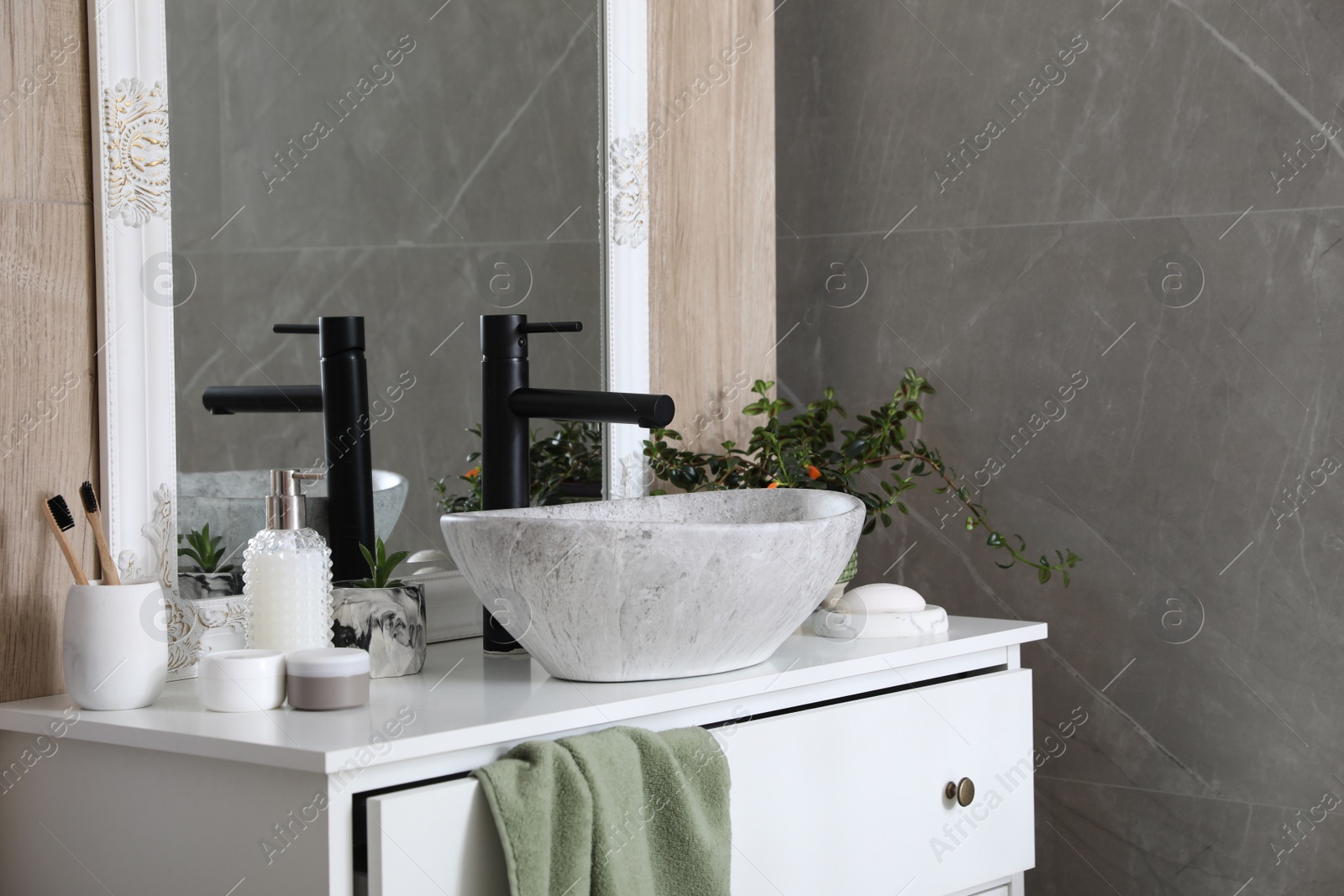 Photo of Chest of drawers with vessel sink, toiletries and houseplants in bathroom. Interior design