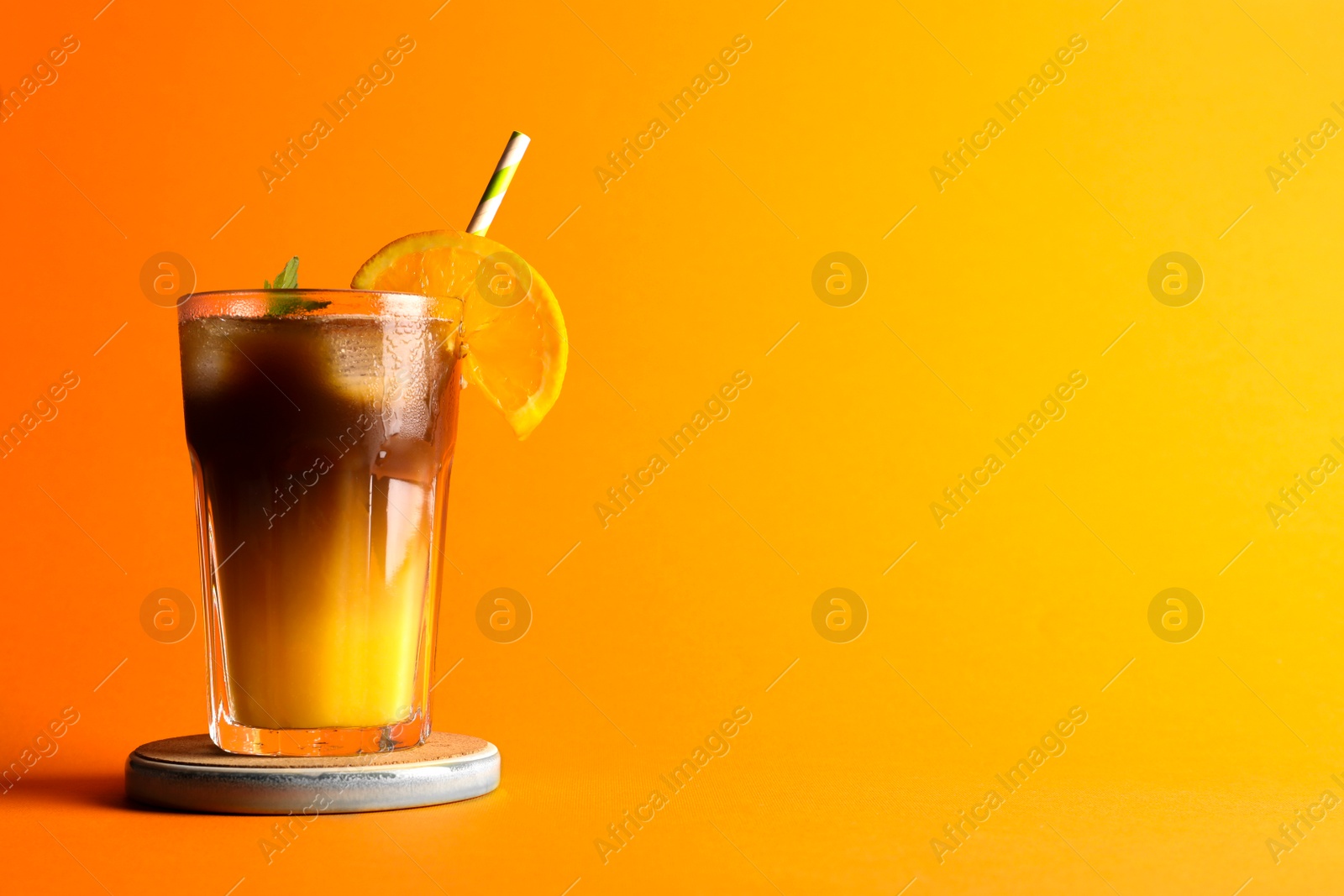 Photo of Tasty refreshing drink with coffee and orange juice on bright color background, space for text