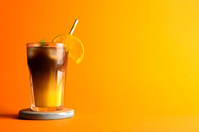 Tasty refreshing drink with coffee and orange juice on bright color background, space for text