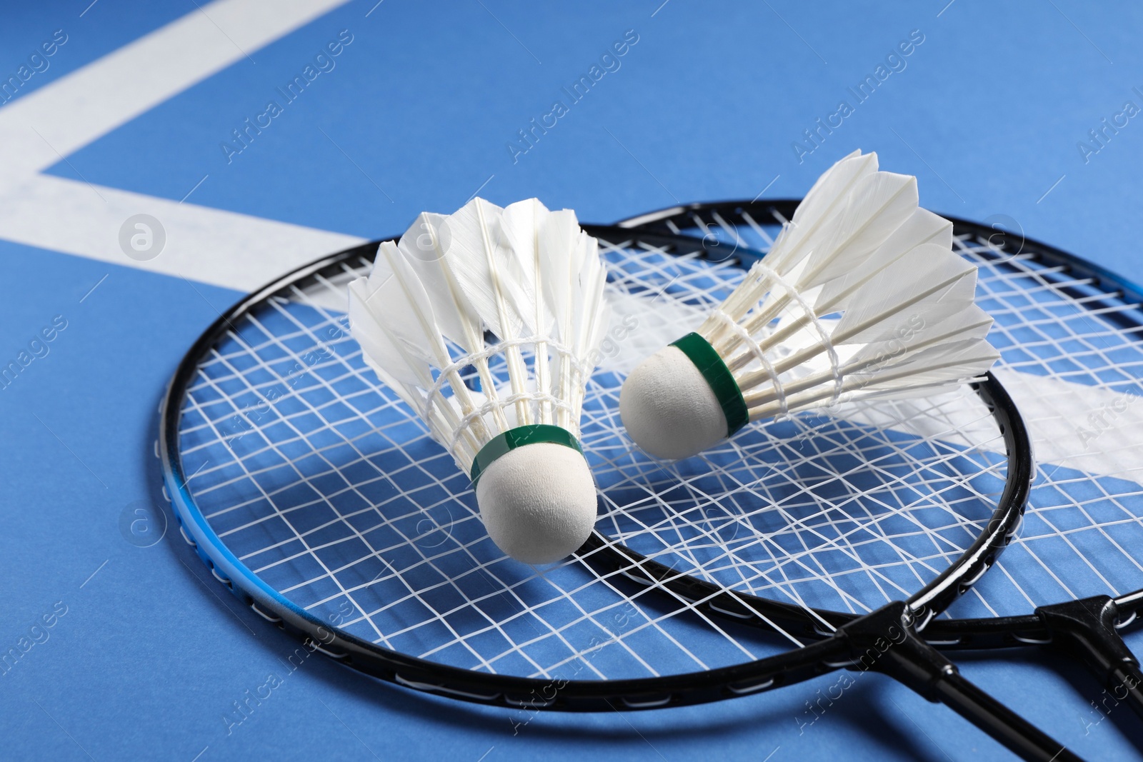 Photo of Feather badminton shuttlecocks and rackets on blue background, closeup